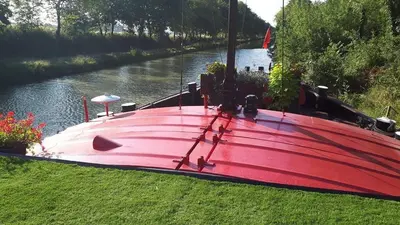 a red boat sitting on the side of a river at Péniche Mirage-chambre d'hôtes in Carcassonne