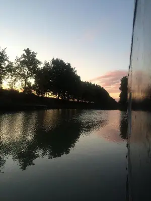 a boat on a river at sunset at Péniche Mirage-chambre d'hôtes in Carcassonne