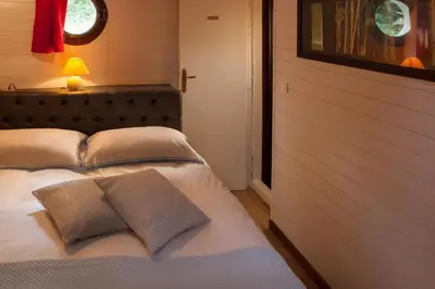a bedroom with a bed with pillows and a window at Péniche Mirage-chambre d'hôtes in Carcassonne