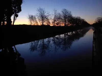a river at sunset with trees in the background at Péniche Mirage-chambre d'hôtes in Carcassonne