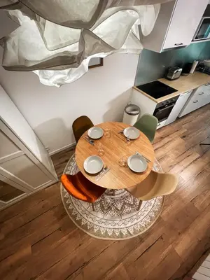 a wooden table in a room with chairs and a kitchen at Au cœur de Castres, logement cosy classé 3*** in Castres