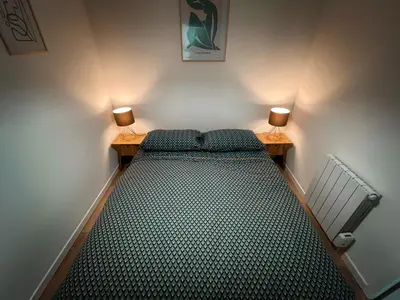 a bed in a room with two lamps on two tables at Au cœur de Castres, logement cosy classé 3*** in Castres