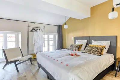a bedroom with a large bed and a chair at Le 11 JACUZZI avec Terrasses Clim Netflix Parking in Carcassonne
