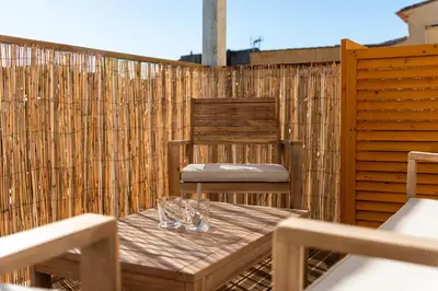 a wooden table and chairs on a patio at Le 11 JACUZZI avec Terrasses Clim Netflix Parking in Carcassonne