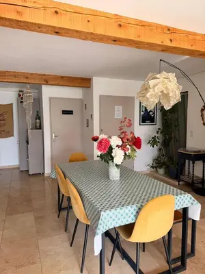 a dining room table with a vase of flowers on it at Maison 6 places, en plein cœur de l’Ariège, proche ski et nature in Lesparrou