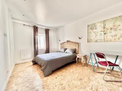 a bedroom with a bed and a red chair at Au pied de la Cité in Carcassonne
