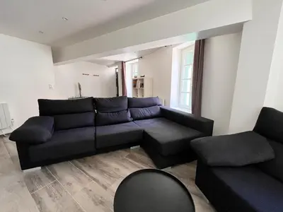 a living room with a black couch and a chair at Au pied de la Cité in Carcassonne