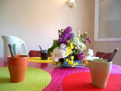 a table with two cups and a vase of flowers at Maison charmante à Aignes avec jardin et barbecue in Aignes