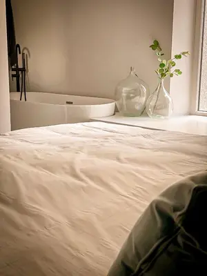 a white bed with a vase on a table with a window at Vins de Dagne in Montlaur