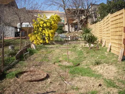 a house with a stone wall next to a fence at Un havre de paix in Aigues-Vives