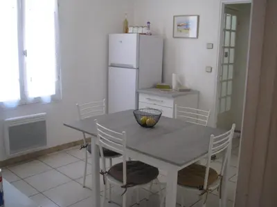 a kitchen with a table with chairs and a refrigerator at Maison la Soleiade in Carcassonne