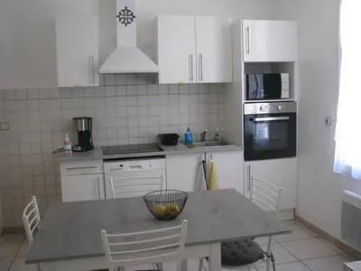 a kitchen with white cabinets and a table with chairs at Maison la Soleiade in Carcassonne