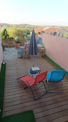 two chairs and an umbrella on a wooden deck at Casa Vignes & Soleil in Puisserguier