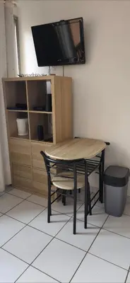 a table with a chair and a tv on a wall at LOCATION STUDIO EN BORD DE PLAGE A GRUISSAN in Gruissan