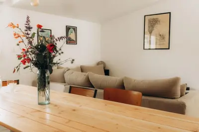 a vase of flowers on a wooden table in a living room at Gîtes Chaleureux écoresponsable in Montesquieu-Lauragais