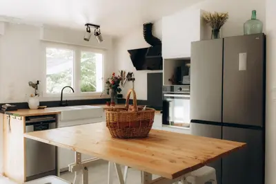 a kitchen with a wooden table and a refrigerator at Gîtes Chaleureux écoresponsable in Montesquieu-Lauragais