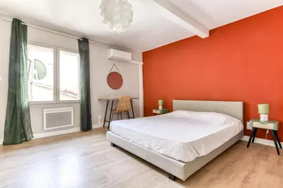 a bedroom with an orange wall and a bed at L'Émeraude de la Cité - Netflix - Clim - Proche Cité in Carcassonne