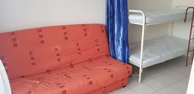 a room with a bunk bed and a red suitcase at Gruissan studio aux Amarines au bord de la plage du Grazel in Gruissan