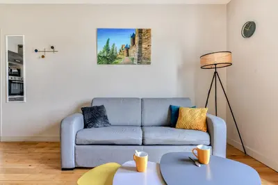 a living room with a couch and a table at Le Soleil du Lac - Parking Privatif - Terrasse - Netflix - Clim in Carcassonne