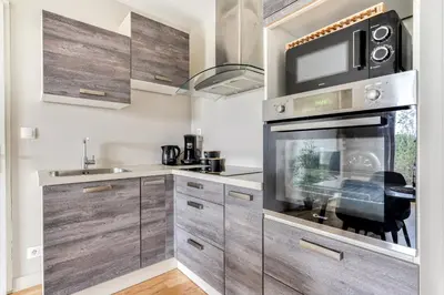a kitchen with wooden cabinets and a microwave at Le Soleil du Lac - Parking Privatif - Terrasse - Netflix - Clim in Carcassonne