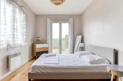a bedroom with a bed and a large window at Le Soleil du Lac - Parking Privatif - Terrasse - Netflix - Clim in Carcassonne