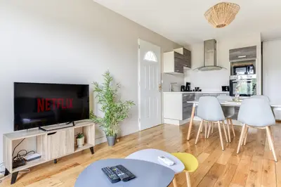 a living room with a tv and a kitchen at Le Soleil du Lac - Parking Privatif - Terrasse - Netflix - Clim in Carcassonne