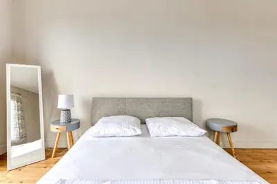 a bedroom with a large white bed with two tables at Le Soleil du Lac - Parking Privatif - Terrasse - Netflix - Clim in Carcassonne