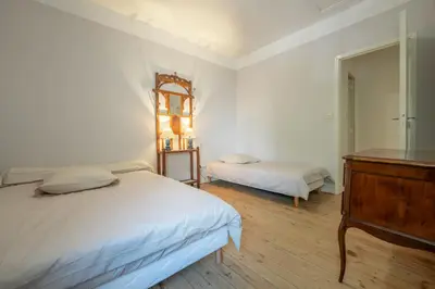 a white bedroom with two beds and a dresser at Chez papy Charles in Carcassonne
