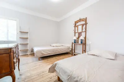 a white bedroom with two beds and a mirror at Chez papy Charles in Carcassonne