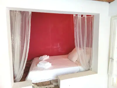 a small bed in a room with a red wall at OCC34 - Capestang - Vigneron in Capestang