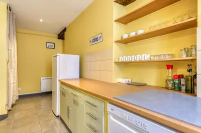 a kitchen with yellow walls and a white refrigerator at Maison du capitole in Narbonne
