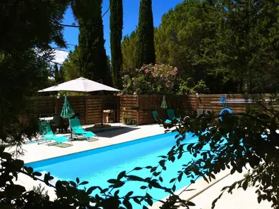 a swimming pool with two chairs and an umbrella at Gîte en pleine nature - Parc, Piscine, Jacuzzi in Brézilhac