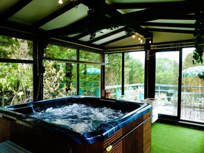 a large blue tub in a room with windows at Gîte en pleine nature - Parc, Piscine, Jacuzzi in Brézilhac