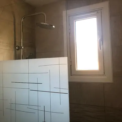 a bathroom with a shower with a window and a white cabinet at Gruissan (Aude) Appartement calme, vue sur port de plaisance -Clim, Empl.Parking in Gruissan