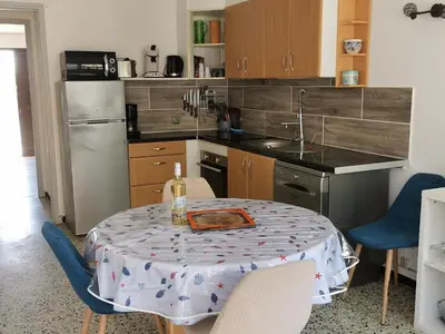 a kitchen with a table with a bottle of wine on it at Pavillon T3 proche de la plage TERRASSE GARAGE PARKING in Port-la-Nouvelle