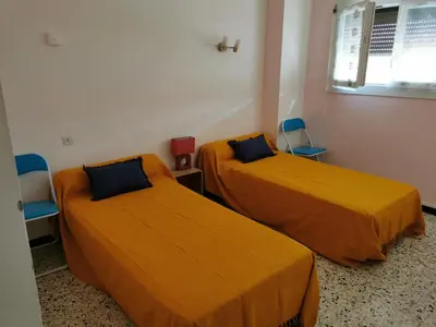 two beds in a room with orange sheets and chairs at Pavillon T3 proche de la plage TERRASSE GARAGE PARKING in Port-la-Nouvelle