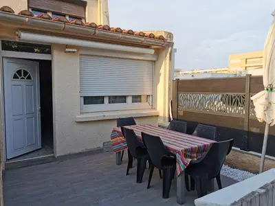 a patio with a table and chairs on a deck at Pavillon T3 proche de la plage TERRASSE GARAGE PARKING in Port-la-Nouvelle
