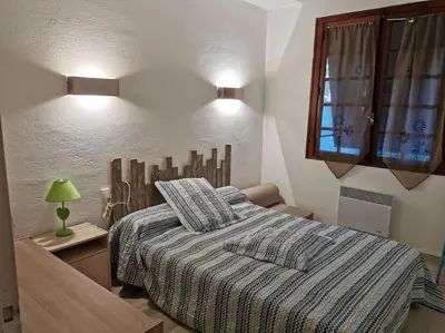 a bedroom with a bed with a striped blanket and a window at villa plain pied 4 chambres à 100m de la plage in Port-la-Nouvelle