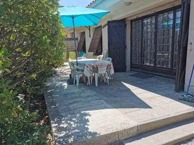 a patio with a table and chairs and an umbrella at villa plain pied 4 chambres à 100m de la plage in Port-la-Nouvelle