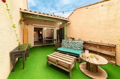 a patio with a couch and a table and chairs at Charmant appartement à Sigean - 23 m² - Climatisation in Sigean