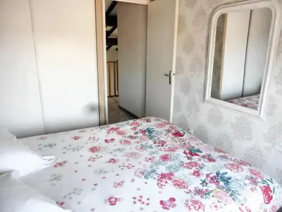 a bedroom with a bed with a floral bedspread and a mirror at Maison avec jardin à Sigean - Confort et tranquillité in Sigean