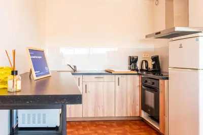 a kitchen with wooden cabinets and a white refrigerator at Appartement moderne vue mer à Port-la-Nouvelle — 42 m² in Port-la-Nouvelle