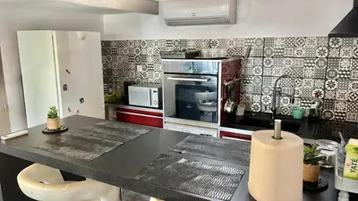 a kitchen with a black counter top and a refrigerator at Chez BEN avec tout le confort clim wifi Netflix gratuit in Castres