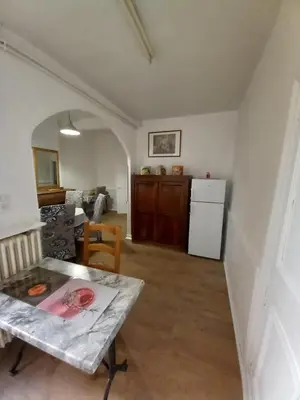 a living room with a table and a refrigerator at La Maison de Chouquette in Limoux