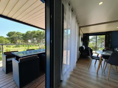 a room with a balcony with a table and chairs at Cottage du Lac 63 in Olonzac
