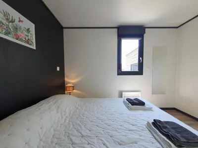 a bedroom with a large white bed with a window at Cottage du Lac 63 in Olonzac