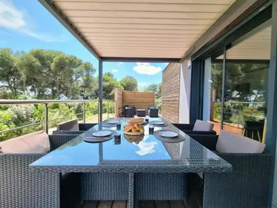 a patio with a table and chairs on a deck at Cottage du Lac 63 in Olonzac