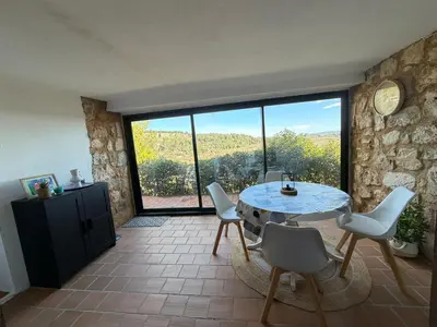 a dining room with a table and chairs and glass doors at Grand T2 bis avec terrasse et vue in Portel-des-Corbières