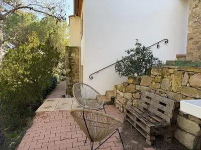 a patio with a bench and a stone wall at Grand T2 bis avec terrasse et vue in Portel-des-Corbières
