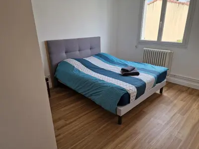 a bedroom with a bed with a blue blanket and a window at Villa BEETHOVEN in Carcassonne